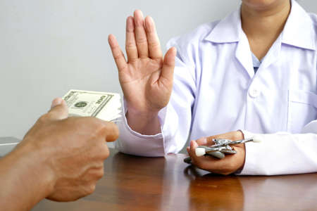 Cropped image of female doctor's hand refusing to take bribe from patient man at doctor office, corruption and bribe in medical conceptの写真素材