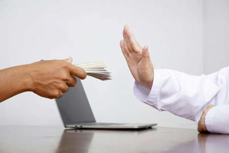 Cropped image of female doctor's hand refusing to take bribe from patient man at doctor office, corruption and bribe in medical conceptの写真素材