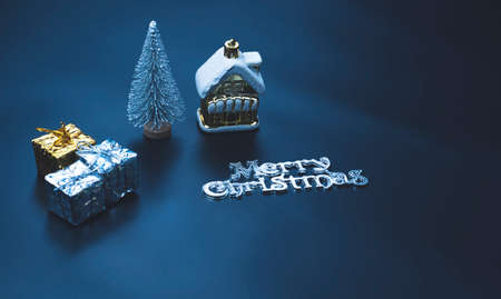 Selective focus at golden miniature house with decorative equipment and "merry Christmas" text on black board in blue night tone style, high angle view with copy spaceの写真素材