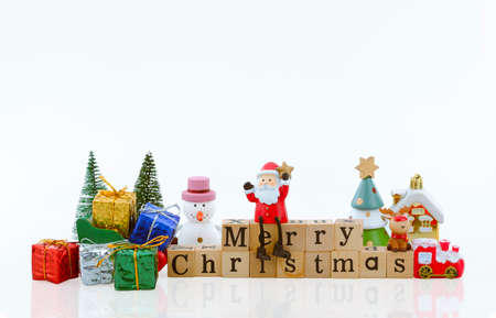 Santa Claus doll on "merry Christmas" wooden word and many Christmas decorations on white backgroundの写真素材