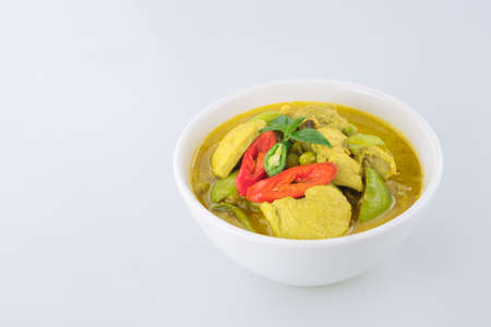 Chicken green curry in white ceramic bowl on white tabletopの写真素材