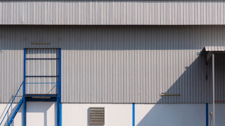 Sunlight and shadow on stairway and side door surface of corrugated metal warehouse building