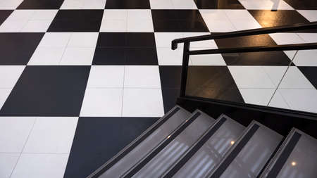 Part of modern stairway on chessboard tile floor in high angle view