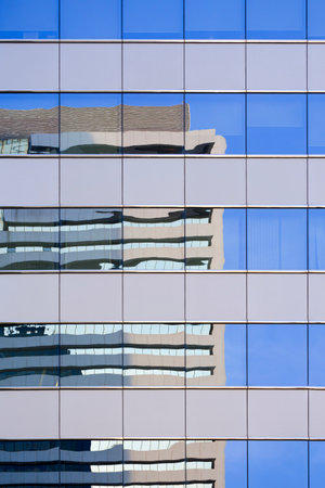 Abstract reflection pattern of building on blue glass wall surface of modern building in vertical...