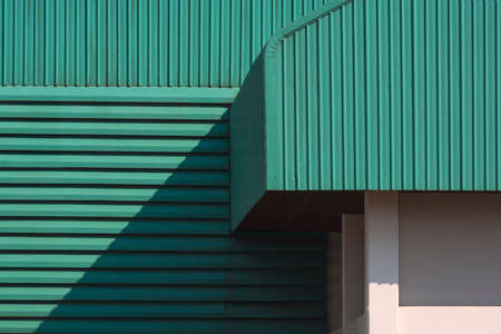 Sunlight and shadow on part of green corrugated metal roof with louver on the wall of large factory buildingの写真素材