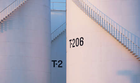 Mild sunshine on spiral staircase surface of the old 3 white storage fuel tanks at morning timeの写真素材