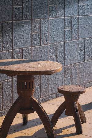 Sunlight and shadow on surface of the old vintage wooden round table set with gray cobblestone tile...