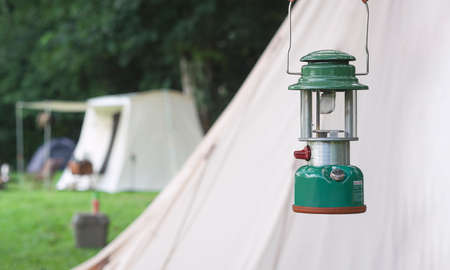 Focus at camping acetylene lantern with blurred background of field tents in camping area at natural parklandの写真素材