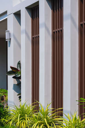 Side view of steel battens on gray wall decoration with green houseplants in home gardening area of...