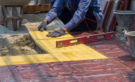 Selective focus at construction worker with work tools is installing and laying concrete tiles floor...