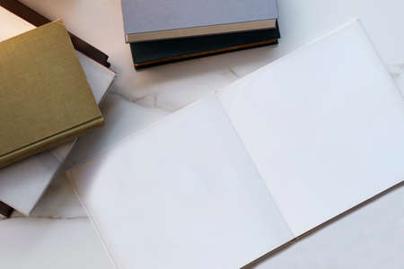Top view of blank photo book page with various old textbooks stack on white marble deskの写真素材