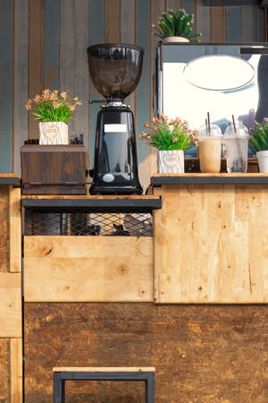 Grinder and coffee maker with artificial flower vase on wooden counter of mini street coffee shop in vintage style and vertical frameの写真素材
