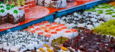Various colorful mini cakes for sale on shelf in outdoor market, selective focusの写真素材