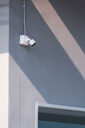 Perspective side view of security camera and flexible metal conduit with part of glass window on...
