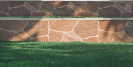 Sunlight and shadow on surface of doorsteps tile floor with blurred green artificial turf in front...