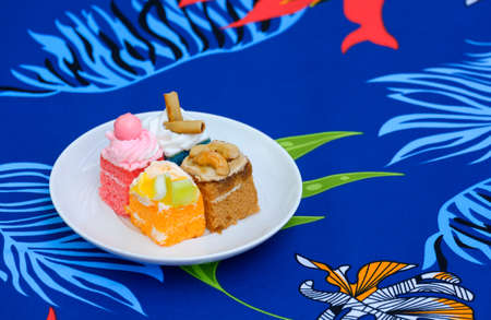 4 mini cakes in white dish on colorful foliage pattern of tablecloth