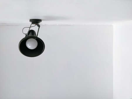 Low angle view of black modern wall lamp on white cement wall with ceiling in home office roomの写真素材