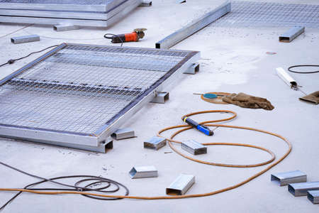 Steel mesh fence panels, electrode holder, red angle grinder with various hand tools on concrete...