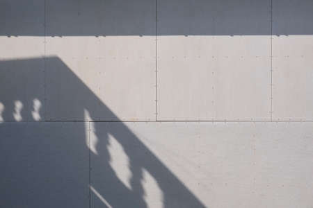Sunlight and balcony shadow on surface of gray gypsum wall background