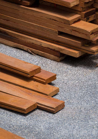 Perspective and selective focus at group of hardwood floorboards with wooden planks stack on gravel stone floor in vertical frameの写真素材