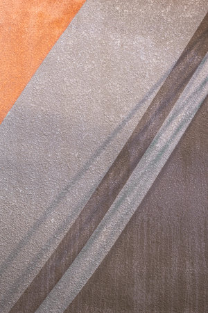 Sunlight and shadow on gray and brown pattern with rough texture of concrete wall background in vertical frame, detail of grunge cement surfaceの写真素材