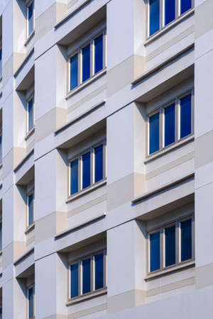 Low angle and perspective side view of multiple closed blue glass windows on office building wall in...
