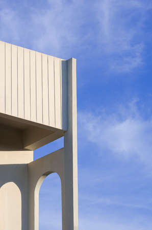 Low angle view of arch wall on balcony of white building against white clouds on blue sky in...