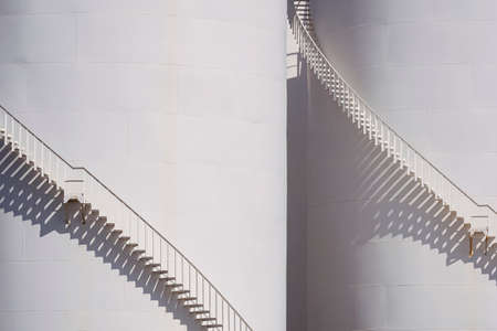 Background of spiral staircases on 2 storage fuel tanks with sunlight and shadow on surface