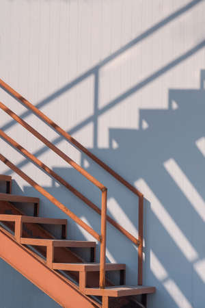 Sunlight and shadow on surface of the old outside metal staircase with gray sandwich panel wall of cold storage in freezer warehouse areaの写真素材