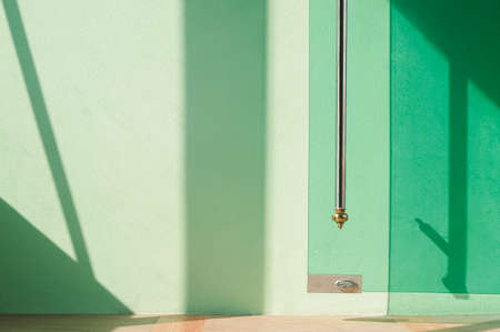 Sunlight and shadow on surface of open glass door on green cement wall in vintage styleの写真素材