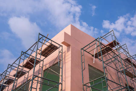 Low angle and perspective view of scaffoldings on pink wall outside of house building structure...
