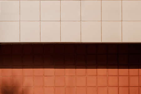 Background abstract square pattern of white tiles and stone brick wall in different level with sunlight and shadow on surfaceの写真素材