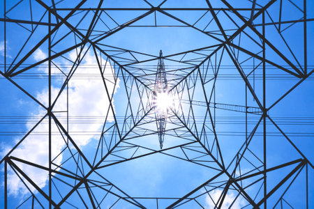 Silhouette ant eyes view of high voltage tower and power lines against sunlight with cloud in blue...