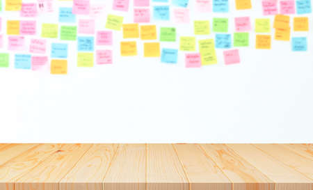 Empty wood counter with blurred many colorful sticky notes on white wall backgroundの写真素材