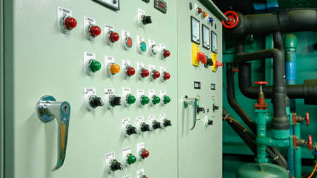 Selective focus at control panel and buttons with pipes in engine room of fishing vessel