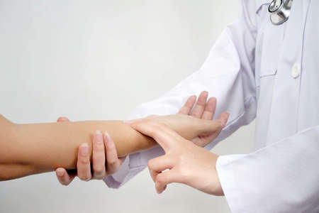 Close up of female doctor hand checking pulse of her patient in hospital room