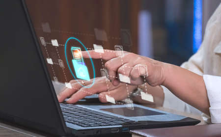 Businesswoman using laptop and touching on internet cloud document storage technology icon virtual screen with document management systemの写真素材