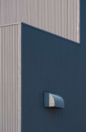 Sunlight and shadow on surface of air duct ventilation on gray corrugated metal industrial building in perspective side view and vertical frameの写真素材