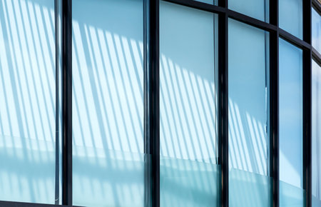 Sunlight and shadow on surface of curve glass building wall with white sunshade inside the office...