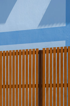 Wooden fence divides the boundaries of house near the blue building wall in vertical frameの写真素材