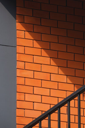 Light and shadow on surface of brick and gray concrete wall with steel balustrade on balcony of...