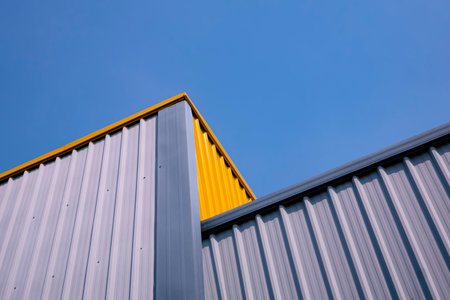 Bottom view of gray and yellow corrugated steel wall of modern warehouse building in different level...