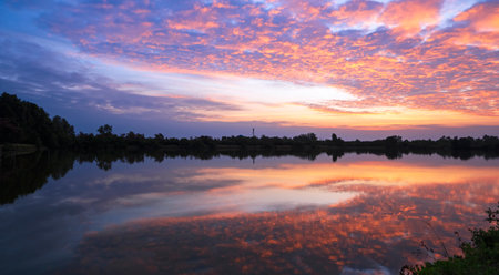 Dramatic colorful dusk sky and majestic orange sunlight clouds over shrimp pond farm with light...