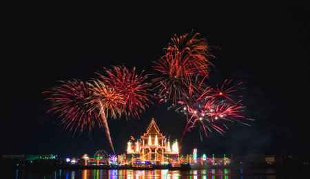 Beautiful fireworks on night sky over Wat Krok Krak Thai temple with decorative lighting and light reflection on river surface in annual festival Samut Sakhon, Thailandの写真素材