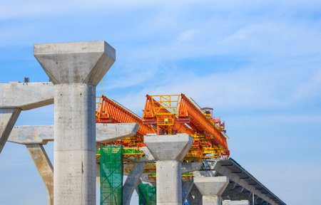 Metal launching gantry Structure for installing concrete typical Segment Joint on foundation of Flyover Expressway in road Construction site against cloudy on blue sky backgroundの写真素材
