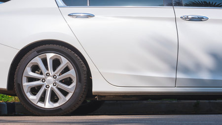 Sunlight reflect on surface of alloy car wheel of white modern sport car parked in parking lot areaの写真素材