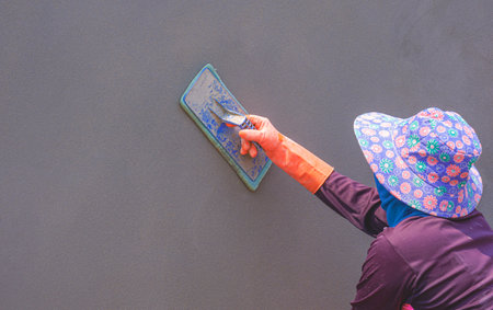 Side view of Female construction worker is Polishing Cement on Fence Wall, perspective side view with copy spaceの写真素材