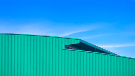 Green Corrugated metal curved Roof of large Warehouse Building in modern style against blue sky Backgroundの写真素材