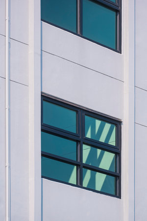 Geometric pattern background of glass windows on modern white building wall with fire escape inside the building, Low angle view and vertical frameの写真素材