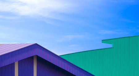 Geometric pattern Background of 2 colorful Corrugated metal Roof of Industrial Warehouse Buildings in modern style against blue sky Backgroundの写真素材
